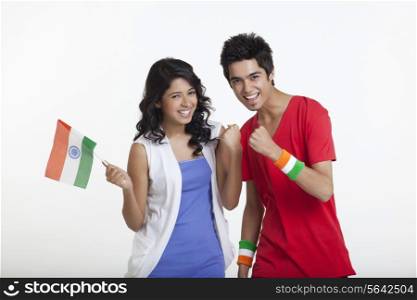 Portrait of young girl holding Indian flag while cheering with friend over white background