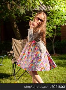Portrait of young girl in sunglasses dancing at yard