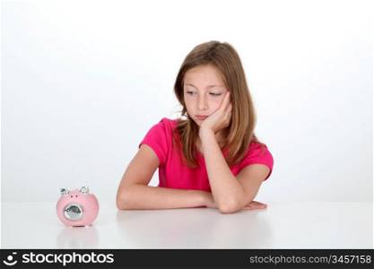 Portrait of young girl looking at piggy bank