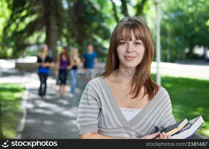 Portrait of young girl smiling while her classmates walking in the background