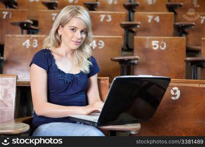 Portrait of young girl using laptop in lecture theatre