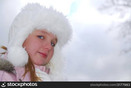 Portrait of young girl wearing white winter hat outside