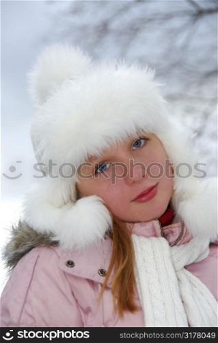 Portrait of young girl wearing white winter hat outside