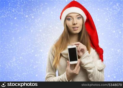 portrait of young girl with christmas style, warm sweater and santa claus hat smiling and showing iphone
