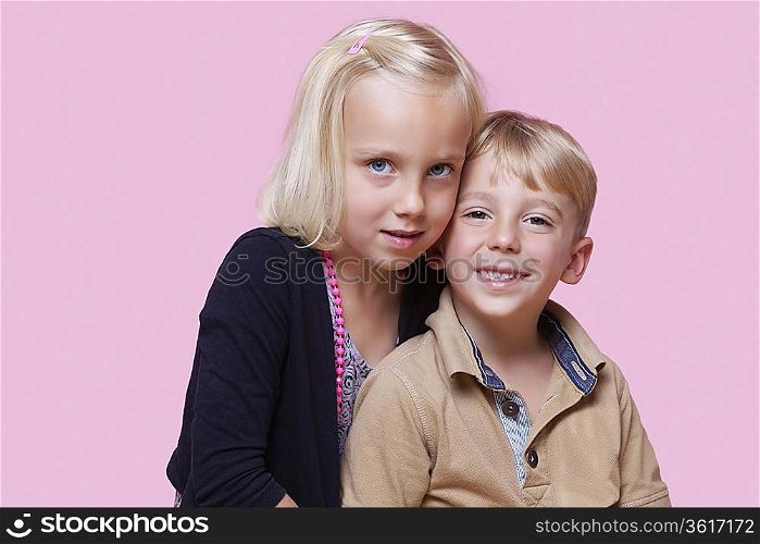 Portrait of young girl with happy brother over pink background