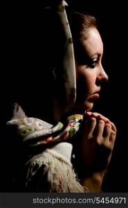 Portrait of young girl with old russian shawl on head on black background. &#xA;