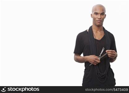 Portrait of young hairstylist standing against white background