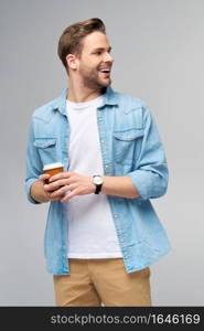 Portrait of young handsome caucasian man in jeans shirt over light background holding cup of coffee to go.. Portrait of young handsome caucasian man in jeans shirt over light background holding cup of coffee to go