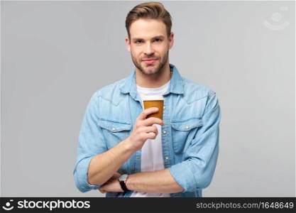 Portrait of young handsome caucasian man in jeans shirt over light background holding cup of coffee to go.. Portrait of young handsome caucasian man in jeans shirt over light background holding cup of coffee to go