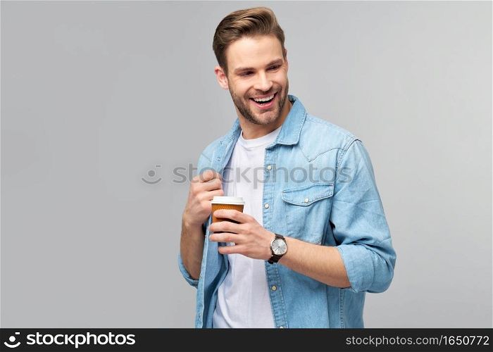 Portrait of young handsome caucasian man in jeans shirt over light background holding cup of coffee to go.. Portrait of young handsome caucasian man in jeans shirt over light background holding cup of coffee to go