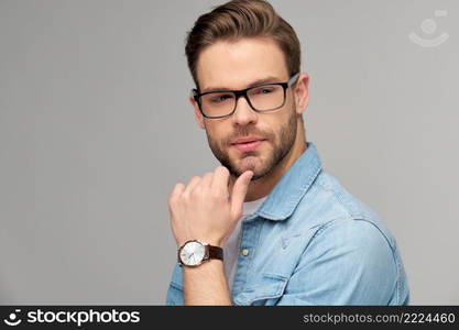 Portrait of young handsome caucasian man in jeans shirt over light background.. Portrait of young handsome caucasian man in jeans shirt over light background