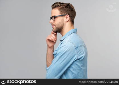 Portrait of young handsome caucasian man in jeans shirt over light background.. Portrait of young handsome caucasian man in jeans shirt over light background