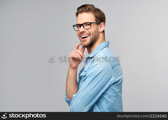 Portrait of young handsome caucasian man in jeans shirt over light background.. Portrait of young handsome caucasian man in jeans shirt over light background