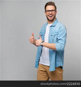 Portrait of young handsome caucasian man in jeans shirt showing big thumb up gesture standing over light background.. Portrait of young handsome caucasian man in jeans shirt showing big thumb up gesture standing over light background