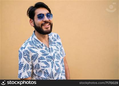 Portrait of young handsome man enjoying summer and wearing summer clothes against yellow background.
