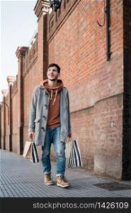 Portrait of young handsome man holding shopping bags while walking on the street. Urban, shop concept.