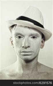 portrait of young handsome man in hat with white make-up