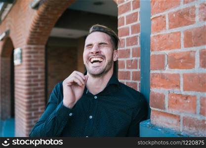 Portrait of young handsome man laughing and walking on the street. Urban concept.