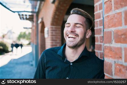 Portrait of young handsome man laughing and walking on the street. Urban concept.