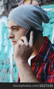 Portrait of young handsome man talking on the phone outdoors. Latin man talking on the phone