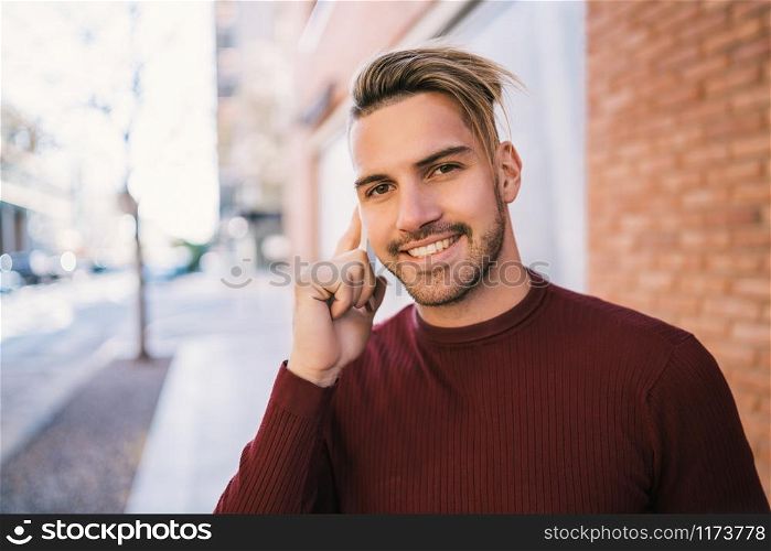 Portrait of young handsome man talking on the phone outdoors in the street. Communication concept.