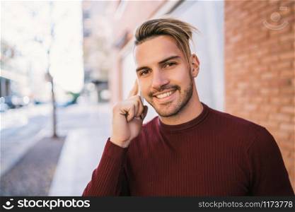 Portrait of young handsome man talking on the phone outdoors in the street. Communication concept.