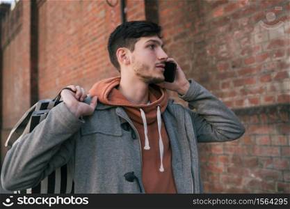 Portrait of young handsome man talking on the phone outdoors in the street. Urban concept. Communication concept.