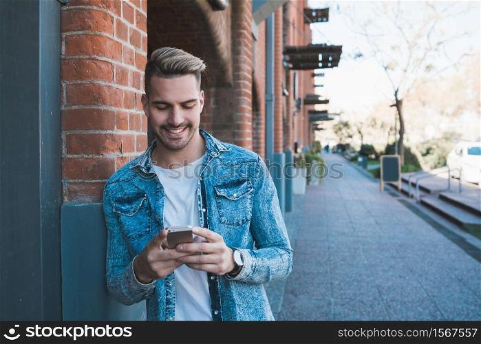 Portrait of young handsome man using his mobile phone outdoors in the street. Communication concept.