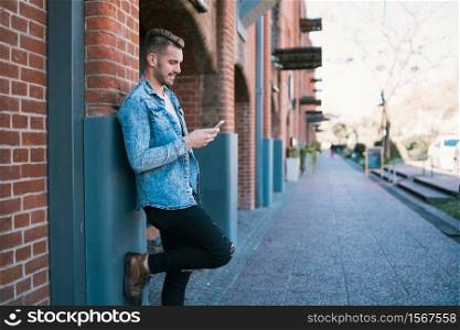 Portrait of young handsome man using his mobile phone outdoors in the street. Communication concept.