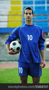 portrait of young handsome soccer player man at football stadium and green grass