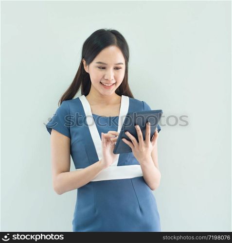 Portrait of young happy asian businesswoman using digital tablet and trump up isolated over white background in work place.