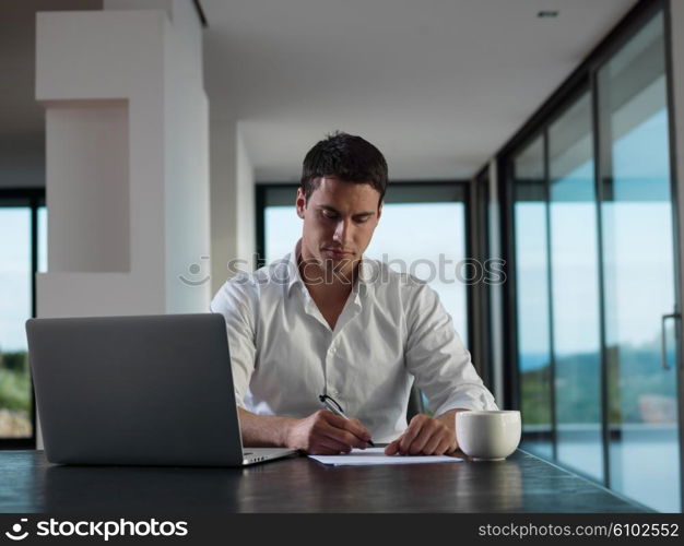 portrait of young happy business man working on laptop computer at home