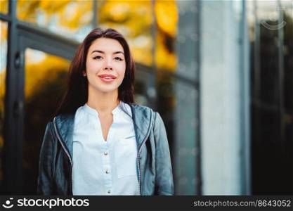 Portrait of young happy business woman near office building. Beautiful caucasian student girl in white sexy blouse standing in the autumn street.. Portrait of young happy business woman near office building. Beautiful caucasian student girl in white sexy blouse standing in the autumn street