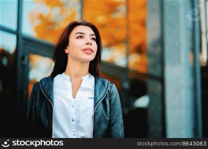 Portrait of young happy business woman near office building. Beautiful caucasian student girl in white sexy blouse standing in the autumn street.. Portrait of young happy business woman near office building. Beautiful caucasian student girl in white sexy blouse standing in the autumn street