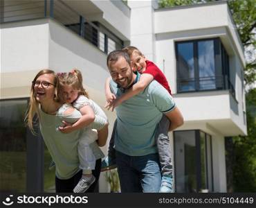Portrait of young happy family with children in the yard in front of their luxury home of villa