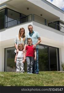 Portrait of young happy family with children in the yard in front of their luxury home of villa