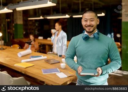 Portrait of young happy freelancer at coworking space. Successful businessman standing in creative office and looking at camera with smile. Portrait of young happy freelancer at coworking space