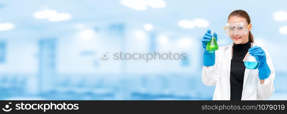 Portrait of young happy scientist or chemist holding test tube in laboratory. Chemical or medical technology research and development concept.