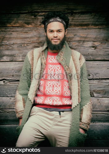 portrait of young hipster, man with beard in front of old vintage wooden house