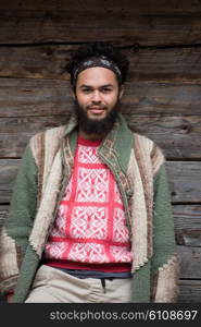 portrait of young hipster, man with beard in front of old vintage wooden house