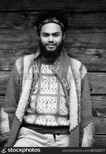 portrait of young hipster, man with beard in front of old vintage wooden house