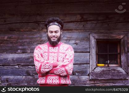 portrait of young hipster, man with beard in front of old vintage wooden house. portrait of young hipster in front of wooden house