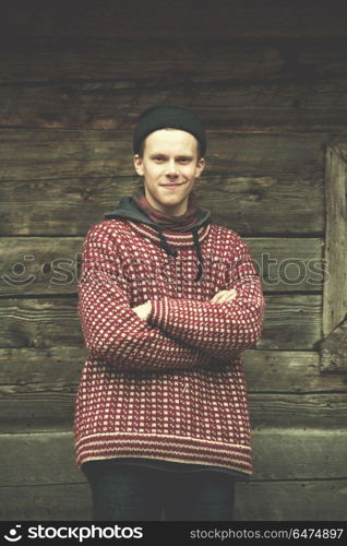 portrait of young hipster, man with nose piercing in front of old vintage wooden house. young hipster in front of wooden house