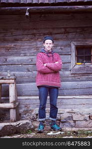 portrait of young hipster, man with nose piercing in front of old vintage wooden house. young hipster in front of wooden house