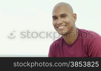 Portrait of young hispanic guy looking at camera near the sea. Copy space
