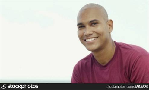 Portrait of young hispanic guy looking at camera near the sea. Copy space