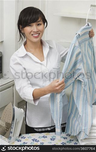 Portrait of young housemaid holding shirt