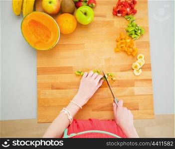 Portrait of young housewife making fruits salad