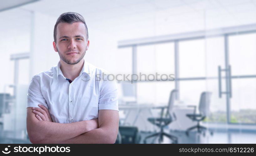 Portrait of young junior businessman in front of his big modern office. Young businessman in his office