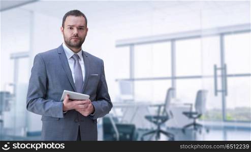 Portrait of young junior businessman in front of his big modern office. Young businessman in his office